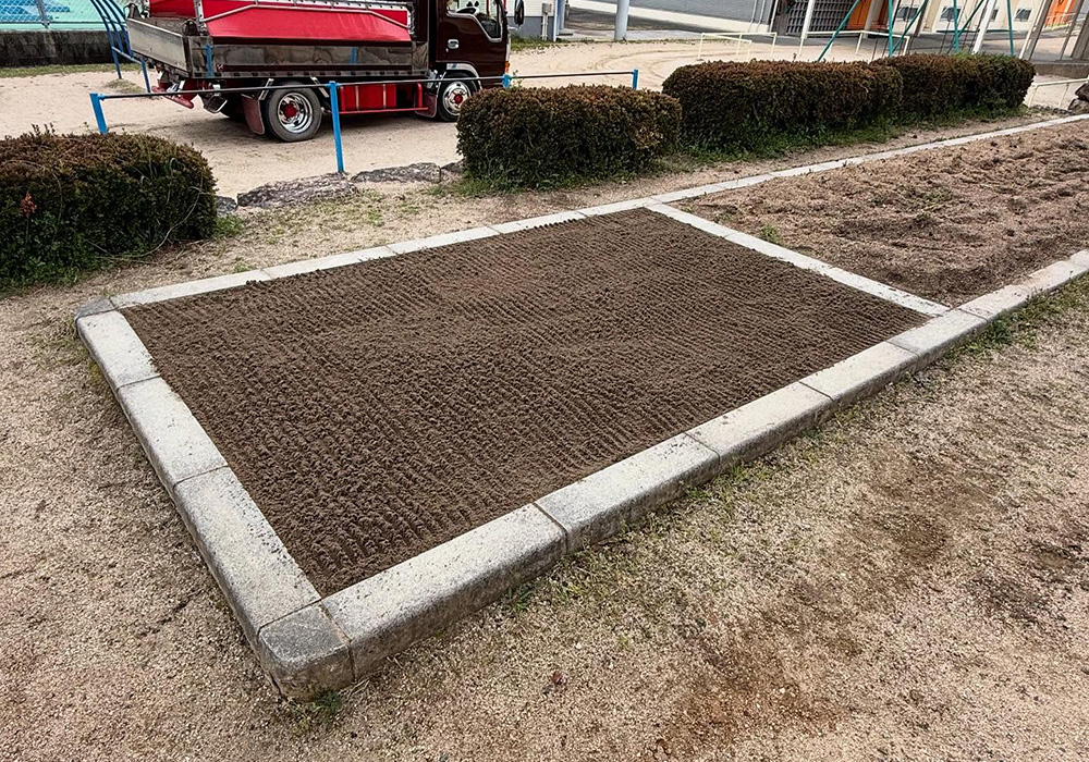 小学校で砂場の砂の入れ替え作業